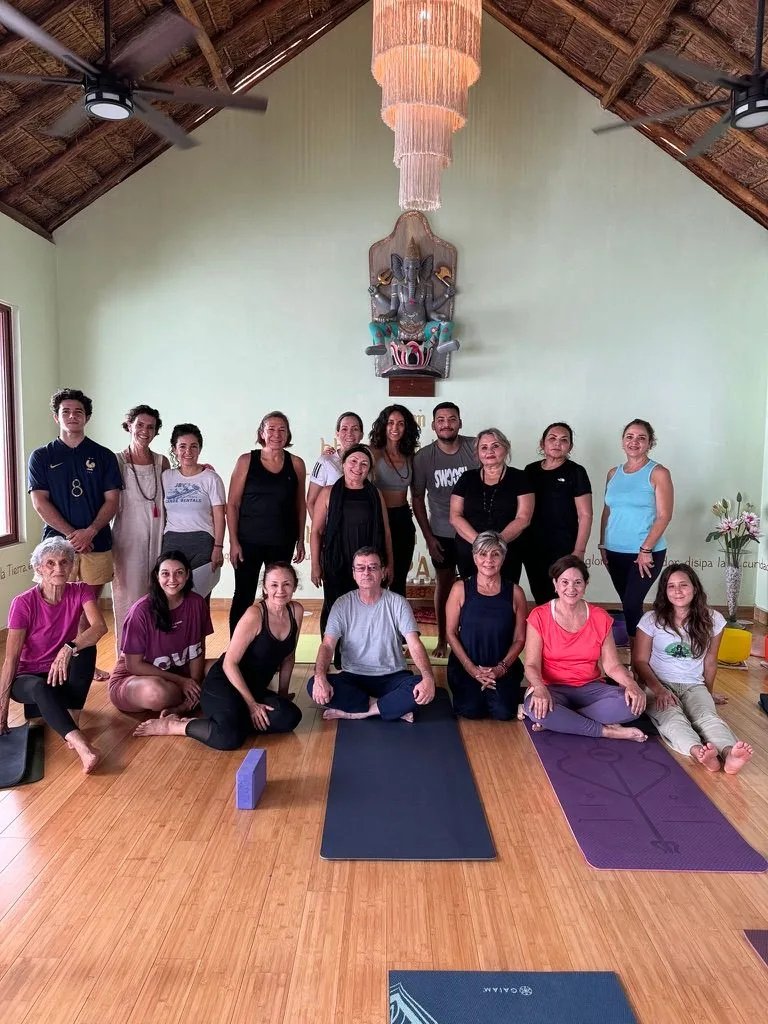 Grupo reunido en un salón de práctica con colchonetas de yoga.